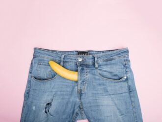 blue jean trousers against a pink background with a yellow peeking out through the fly